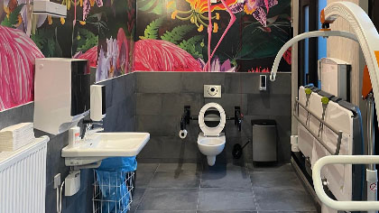 Blick in eine „Toilette für alle“ mit umfassender Ausstattung und auffälliger Wandgestaltung.