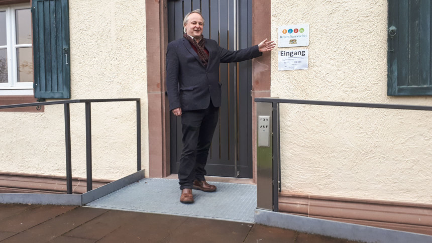 Schulleiter Robert Staufer präsentiert das Signet „Bayern barrierefrei“ am Schuleingang.