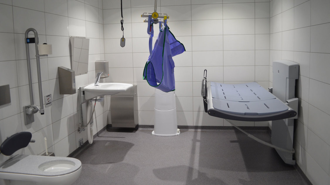Eine „Toilette für alle“ mit Behinderten-WC, unterfahrbarem Waschbecken, Deckenlifter und Pflegeliege.