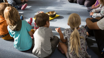 Mehrere Kindergartenkinder sitzen im Kreis um eine Klangschale.