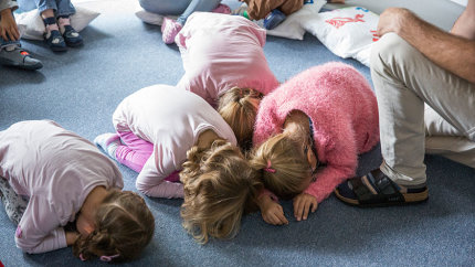 Lena und weitere Kinder kauern auf dem Boden und verstecken ihr Gesicht.