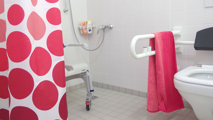 Rollstuhlgerechtes Badezimmer: Blick in die Dusche mit Pflegestuhl.