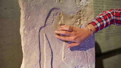 Hand einer Besucherin ertastet eine Relieffigur im Museum.