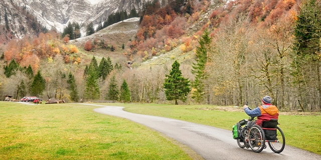 Ein Rollstuhlfahrer fährt auf einem Landweg.