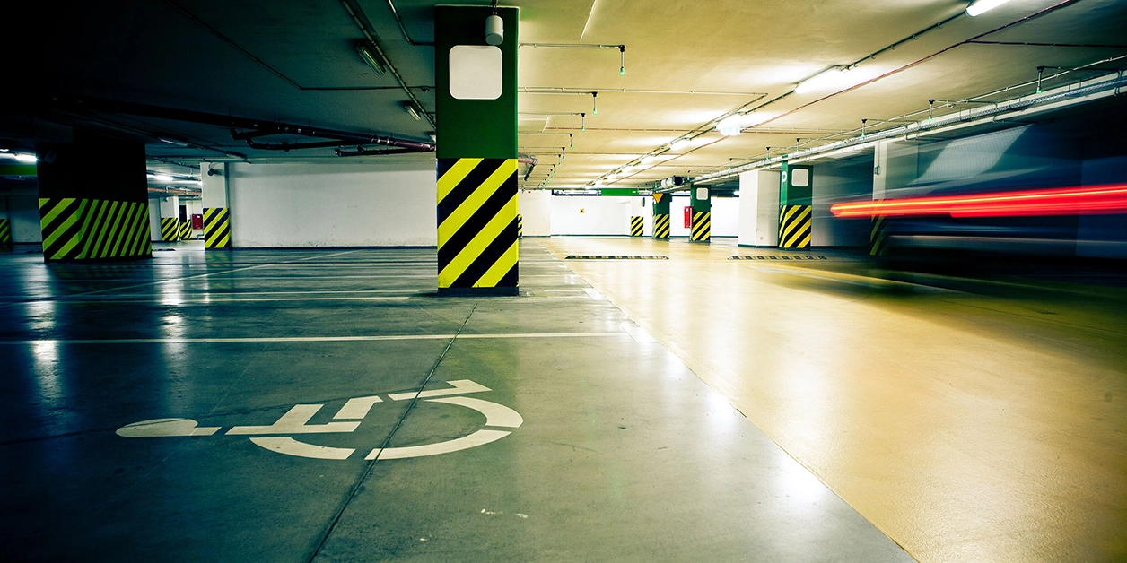 Behindertenparkplatz, erkennbar am Rollstuhl-Symbol auf der Parkfläche, in einer Tiefgarage.