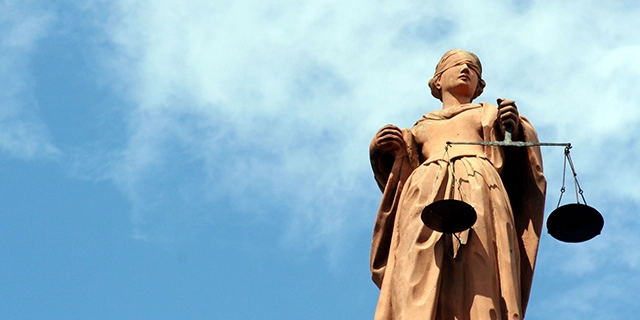 Statue der Justitia, dem antiken Symbol der Gerechtigkeit: eine Frauenfigur mit verbundenen Augen und einer Waage in der linken Hand.