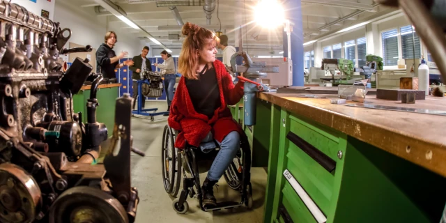 Eine Frau im Rollstuhl arbeitet in einer Werkstatt.