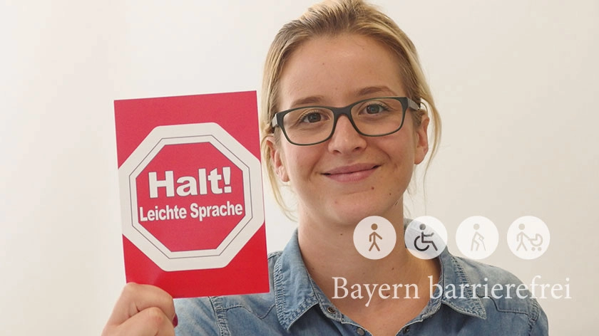 Junge Frau zeigt Schild „Halt! Leichte Sprache“.