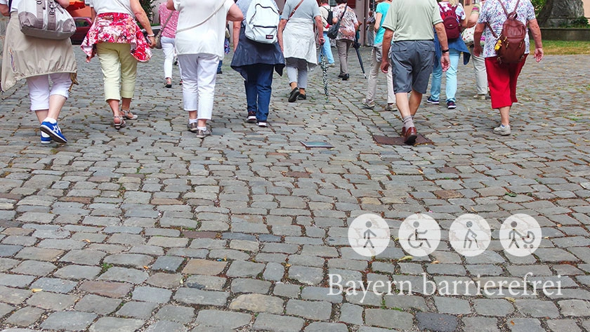 Gruppe älterer Menschen unterwegs auf Kopfsteinpflaster.