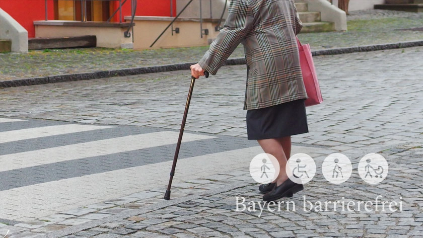 Ältere Dame mit Stock überquert barrierefreien Zebrastreifen.