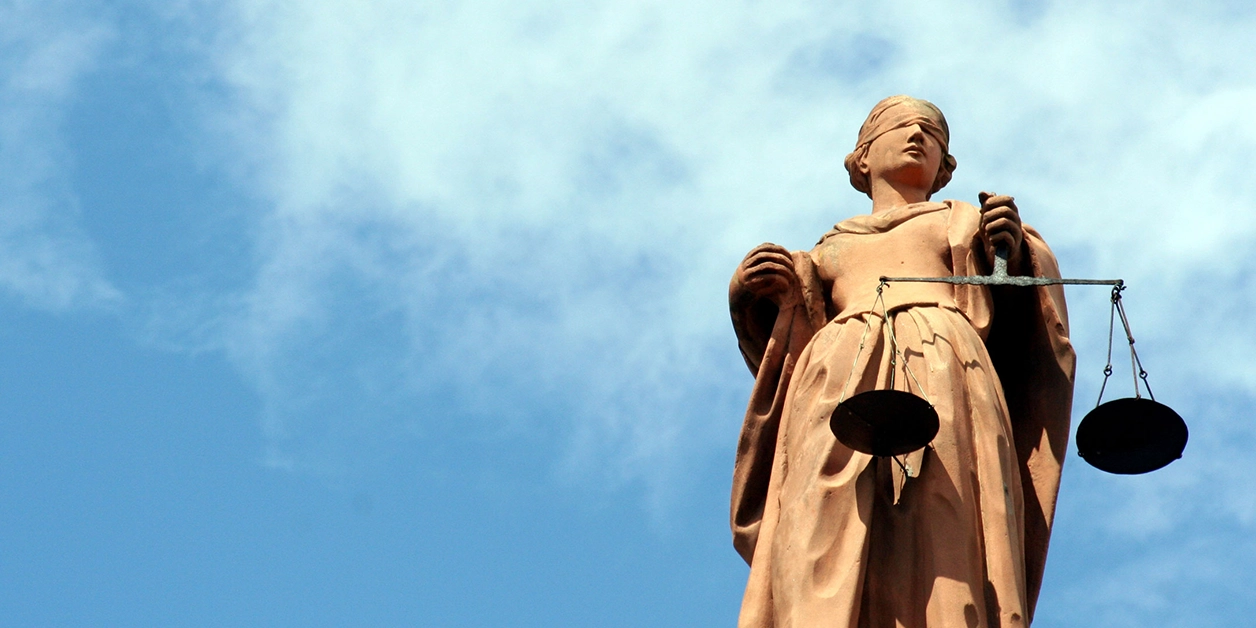 Statue der Justitia, dem antiken Symbol der Gerechtigkeit: eine Frauenfigur mit verbundenen Augen und einer Waage in der linken Hand.