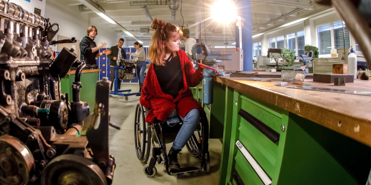 Eine Frau im Rollstuhl arbeitet in einer Werkstatt.