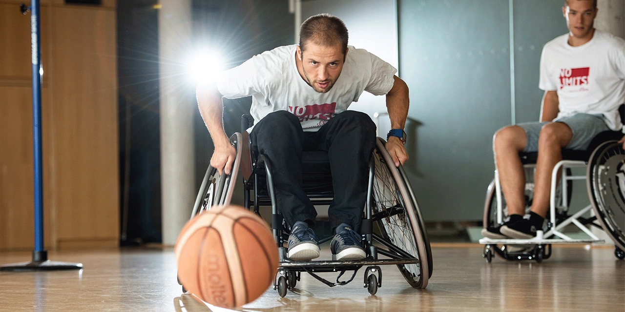 In einer Sporthalle: Zwei Männer beim Rollstuhlbasketball.