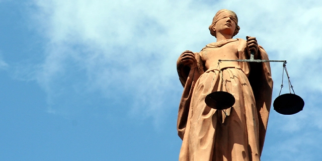 Statue der Justitia, dem antiken Symbol der Gerechtigkeit: eine Frauenfigur mit verbundenen Augen und einer Waage in der linken Hand.