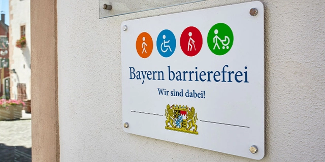 Das Signet „Bayern barrierefrei“ an einer Hauswand.