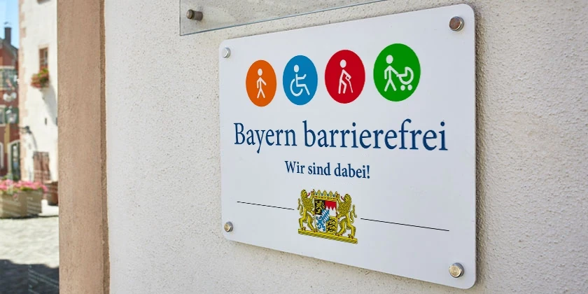 Das Signet „Bayern barrierefrei“ an einer Hauswand.